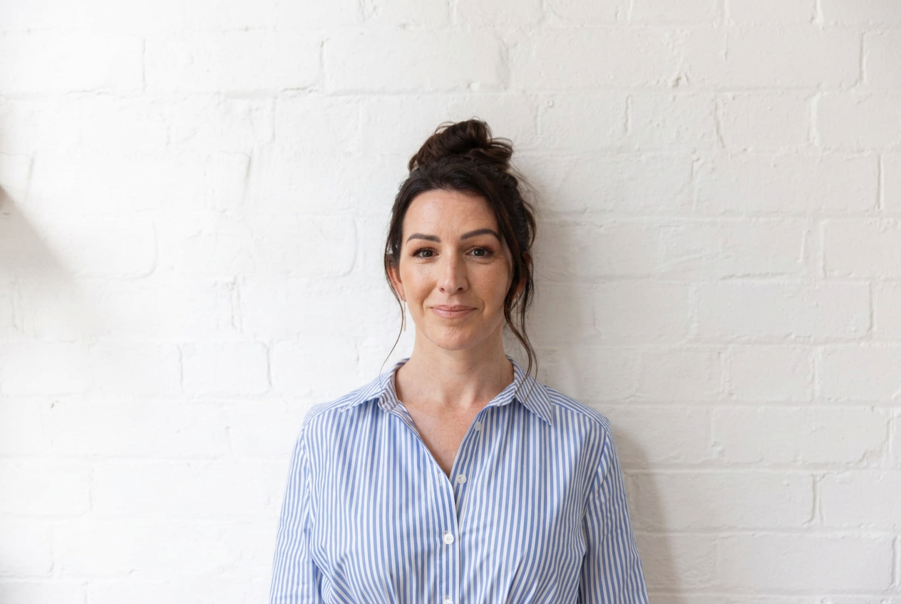 Coach Vickie Saunders standing in front of a white brick wall, smiling